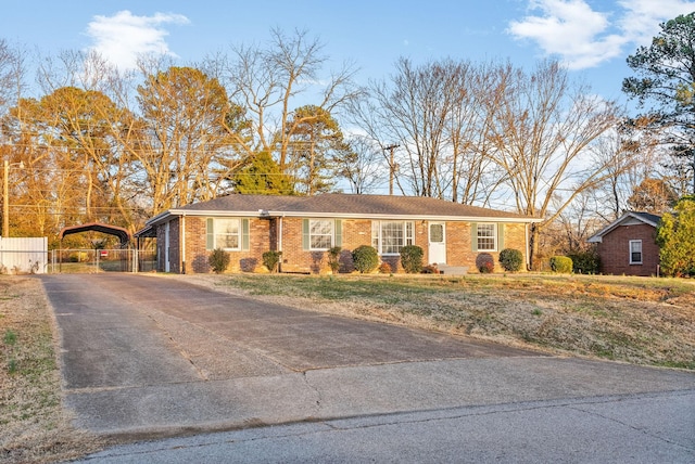 ranch-style house featuring driveway, brick siding, and fence