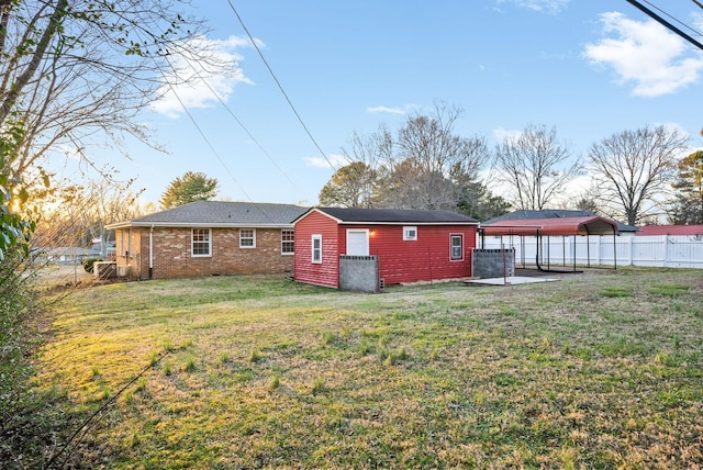 rear view of house with a fenced backyard, a yard, and brick siding