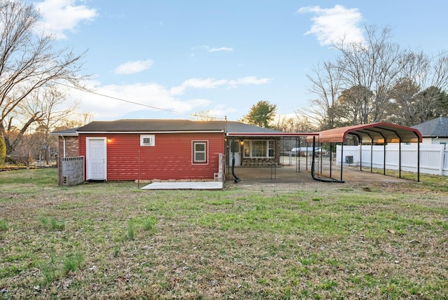 rear view of house with a carport, a yard, and fence