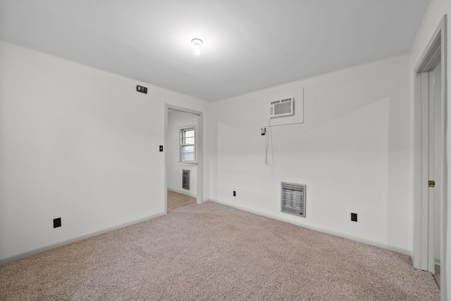 spare room with baseboards, a wall mounted air conditioner, visible vents, and light colored carpet