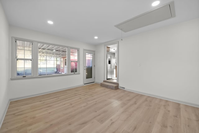 spare room with baseboards, light wood-style flooring, attic access, and recessed lighting