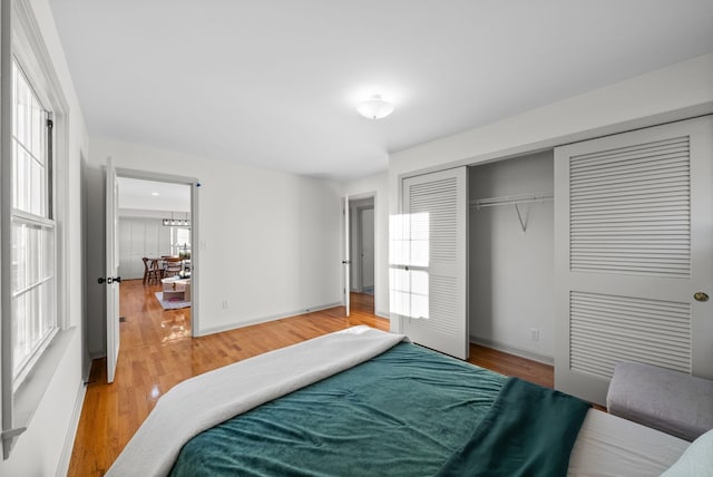 bedroom featuring a closet, light wood-style flooring, and baseboards