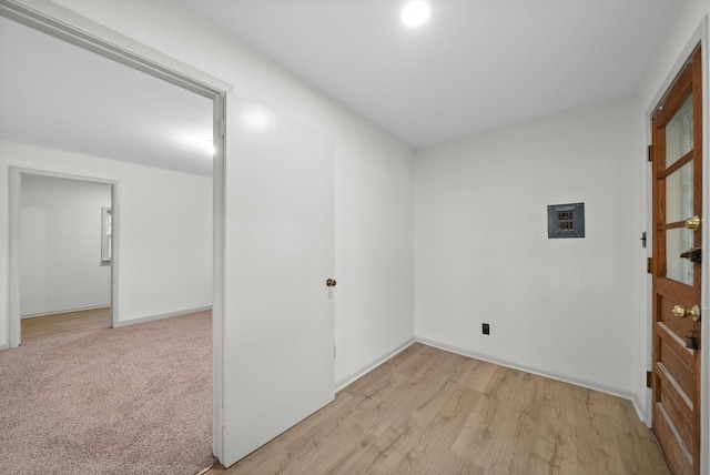 spare room with light wood-type flooring, baseboards, and light colored carpet