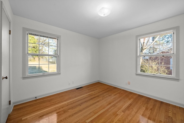 unfurnished room with visible vents, light wood-style flooring, and baseboards