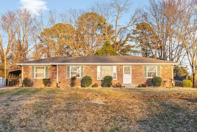 single story home with a carport, a front yard, brick siding, and fence