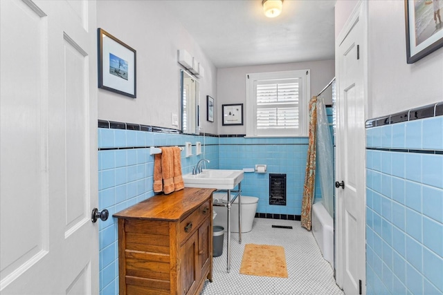 bathroom with tile walls, toilet, heating unit, tile patterned flooring, and a sink