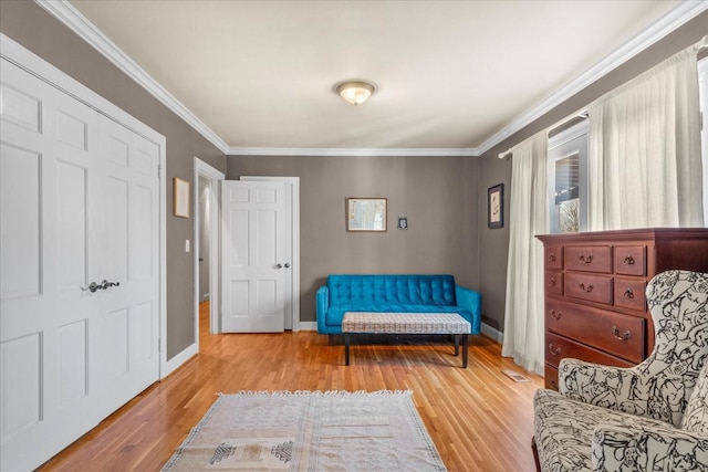 sitting room with ornamental molding, wood finished floors, visible vents, and baseboards