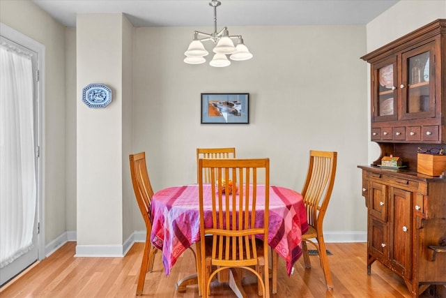 dining room featuring baseboards, light wood finished floors, and an inviting chandelier