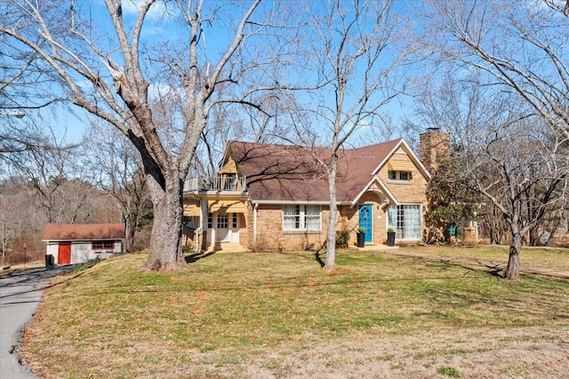 view of front of property with a front lawn, a chimney, and a balcony