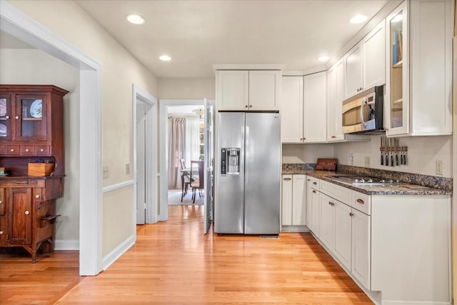 kitchen with stainless steel appliances, white cabinetry, glass insert cabinets, and light wood finished floors