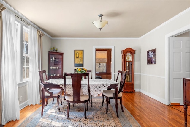 dining room with baseboards, light wood-type flooring, and crown molding