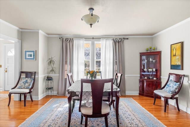 dining room featuring baseboards, light wood-style flooring, and crown molding