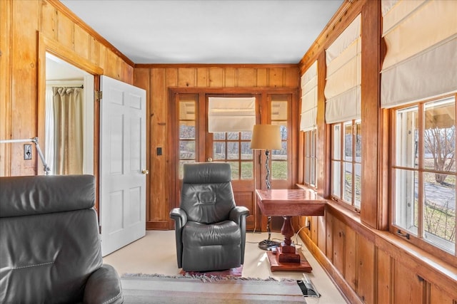 living area with a healthy amount of sunlight, wooden walls, and crown molding