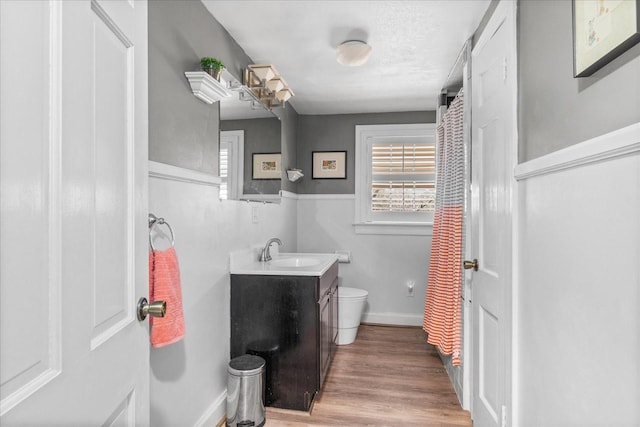 bathroom with wood finished floors, vanity, toilet, and baseboards