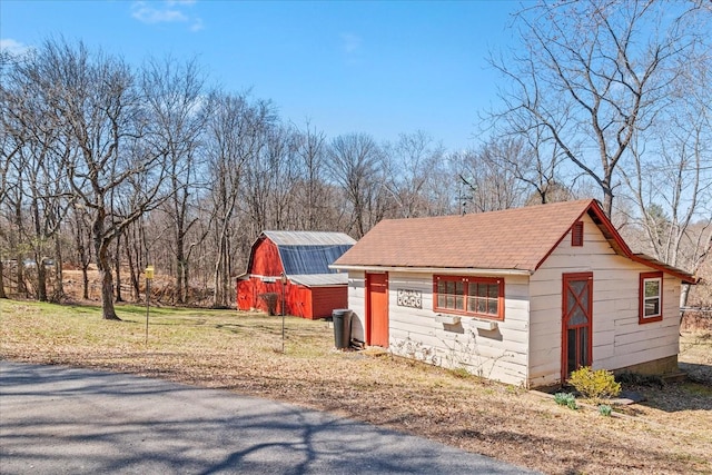 view of home's exterior featuring a barn, a lawn, and an outbuilding