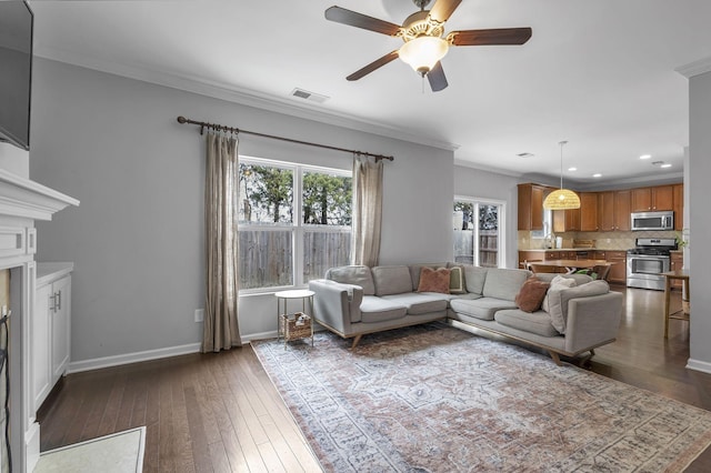 living room featuring ornamental molding, dark wood-style flooring, visible vents, and baseboards