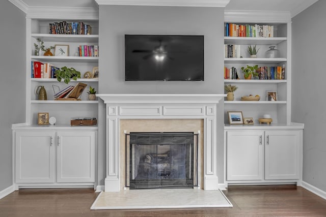 living room with ornamental molding, dark wood-type flooring, a fireplace, and built in features