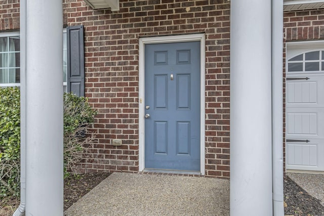 property entrance with a garage and brick siding