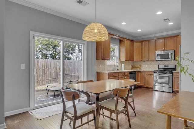 kitchen featuring stainless steel appliances, tasteful backsplash, light countertops, visible vents, and light wood-type flooring