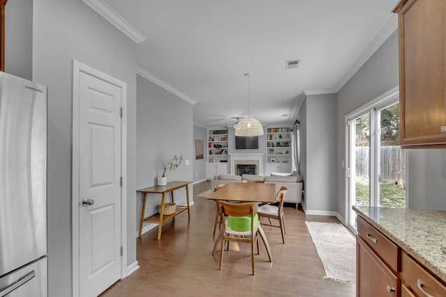 dining space with crown molding, built in shelves, a fireplace, and baseboards