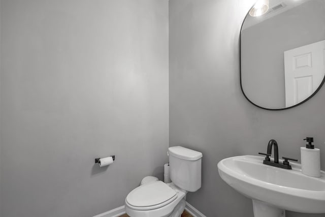 bathroom with visible vents, a sink, toilet, and baseboards