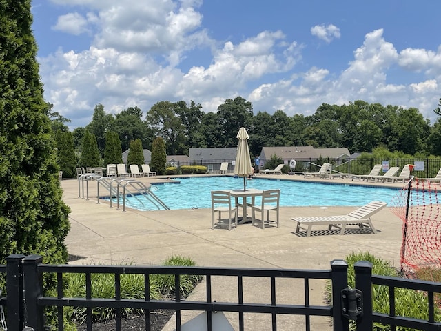 community pool with a patio area and fence