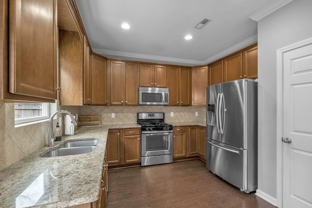 kitchen featuring visible vents, brown cabinets, light stone countertops, stainless steel appliances, and a sink