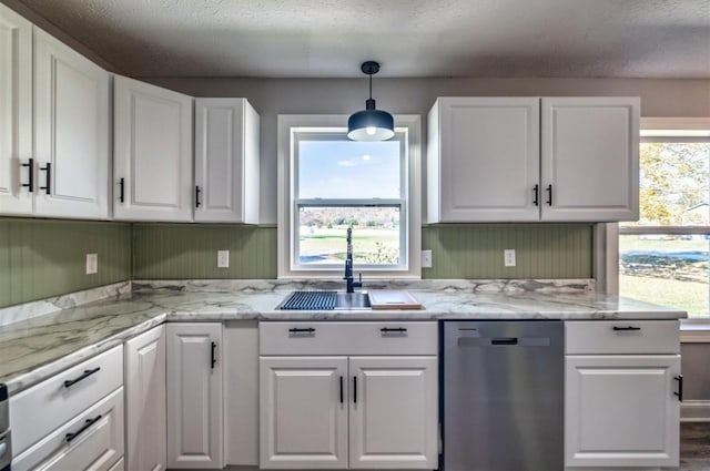 kitchen with pendant lighting, stainless steel dishwasher, white cabinets, a sink, and a textured ceiling