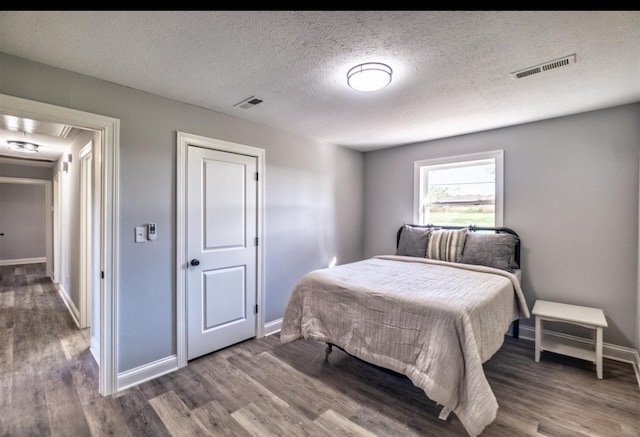 bedroom featuring wood finished floors, visible vents, and baseboards