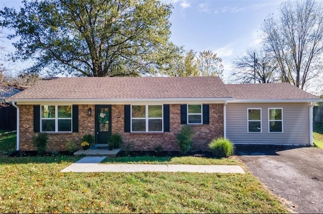 ranch-style home with a front yard, brick siding, driveway, and roof with shingles