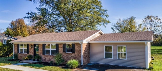 ranch-style home featuring a shingled roof and brick siding