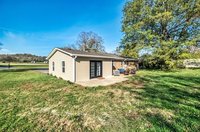 rear view of house with a patio, central AC unit, and a lawn