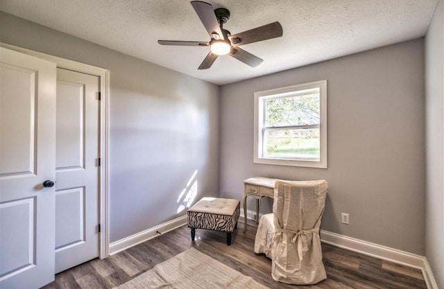 living area with a ceiling fan, baseboards, dark wood finished floors, and a textured ceiling