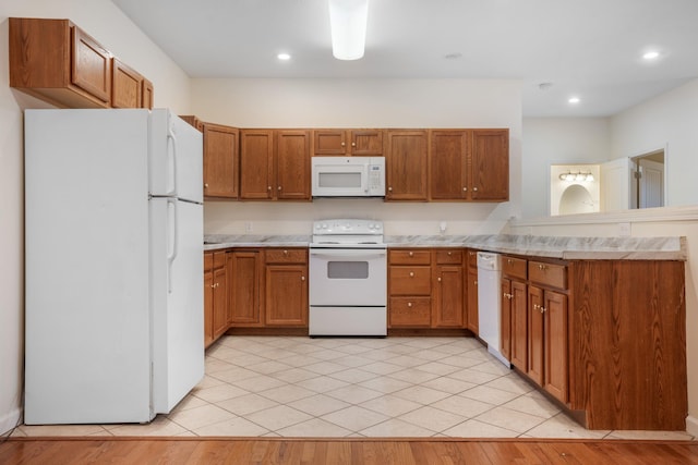 kitchen with a peninsula, white appliances, and brown cabinetry