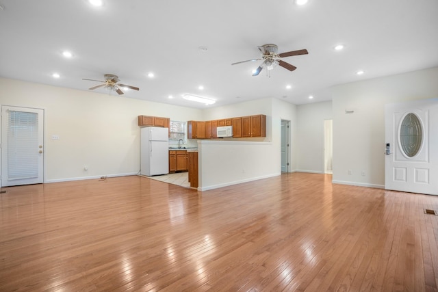 unfurnished living room with ceiling fan, light wood-type flooring, a sink, and recessed lighting