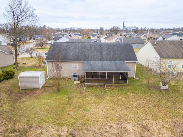 rear view of house featuring a residential view, a sunroom, a yard, and an outdoor structure