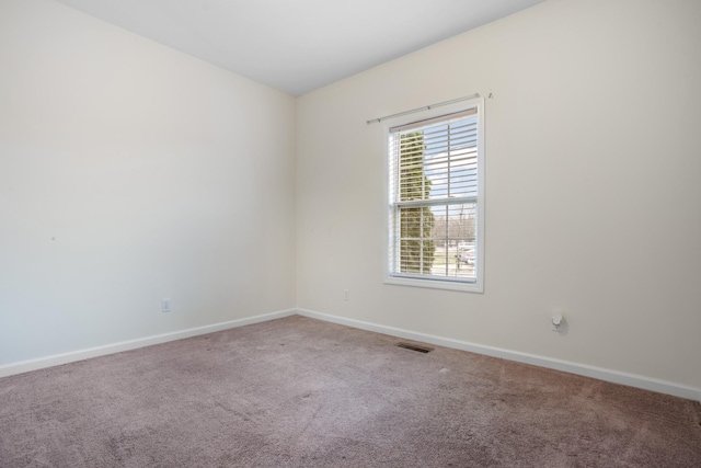 carpeted spare room with visible vents and baseboards