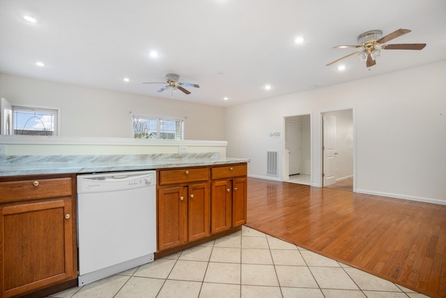 kitchen featuring light tile patterned floors, white dishwasher, visible vents, a ceiling fan, and brown cabinetry