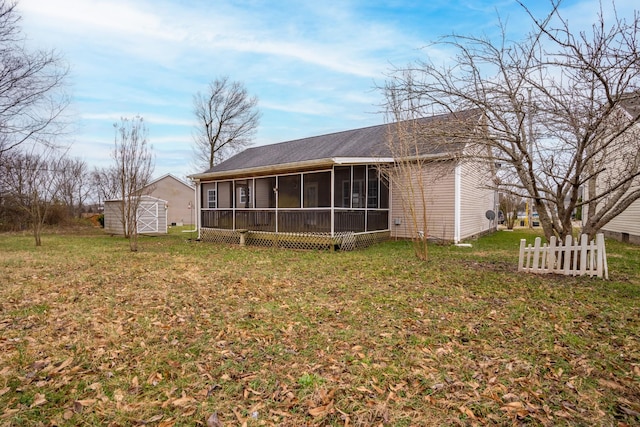 rear view of property featuring a lawn, a sunroom, an outbuilding, fence, and a shed