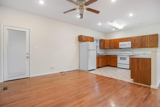 kitchen with white appliances, a sink, visible vents, and brown cabinets