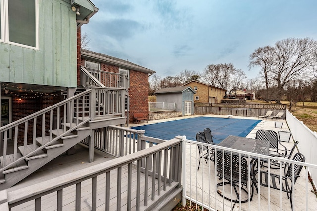 view of swimming pool featuring a fenced in pool, an outbuilding, a patio, stairway, and fence