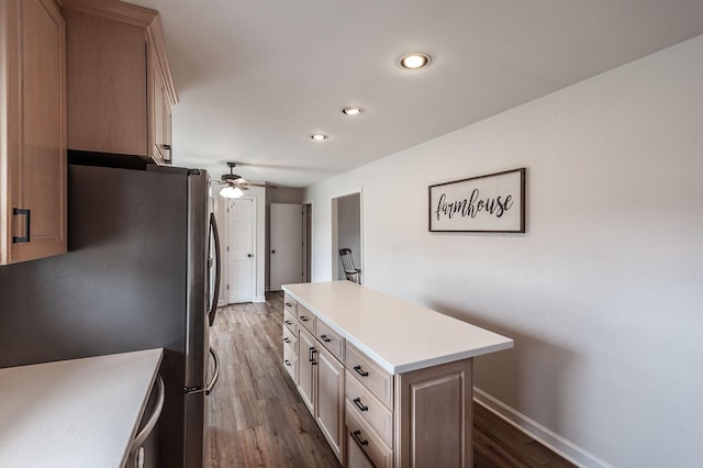 kitchen with light countertops, dark wood finished floors, a kitchen island, and freestanding refrigerator