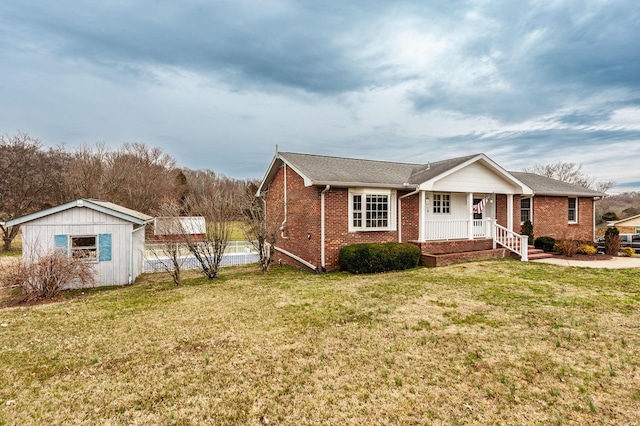 view of front of house featuring brick siding, a front lawn, a porch, and an outdoor structure