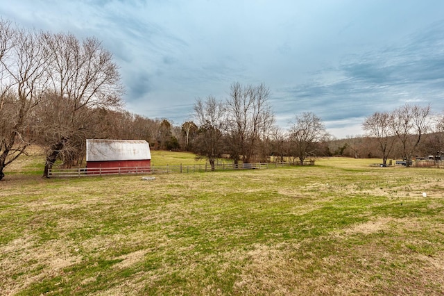 view of yard with a rural view, fence, an outbuilding, and an outdoor structure