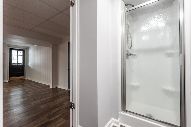 full bathroom with a stall shower, a paneled ceiling, baseboards, and wood finished floors