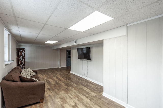 interior space featuring a paneled ceiling, wood finished floors, visible vents, and baseboards