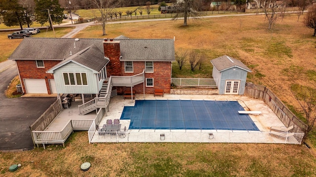 view of swimming pool featuring a wooden deck, a fenced in pool, a fenced backyard, stairs, and an outdoor structure