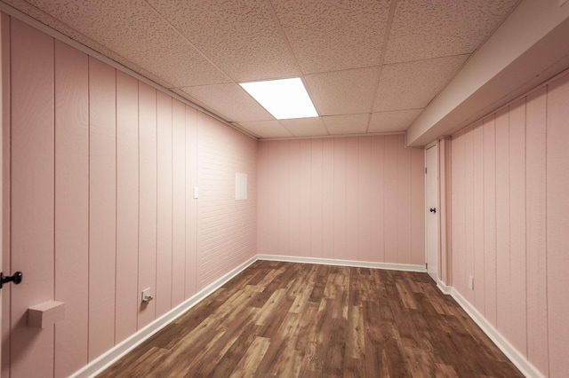 spare room with dark wood-style flooring, a drop ceiling, and baseboards