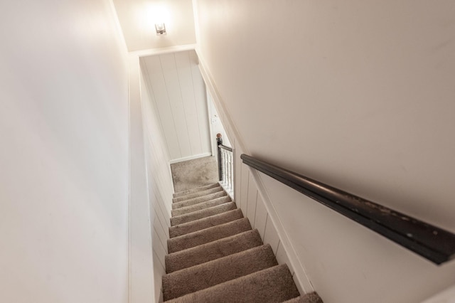 stairway featuring a wainscoted wall, carpet flooring, and a decorative wall