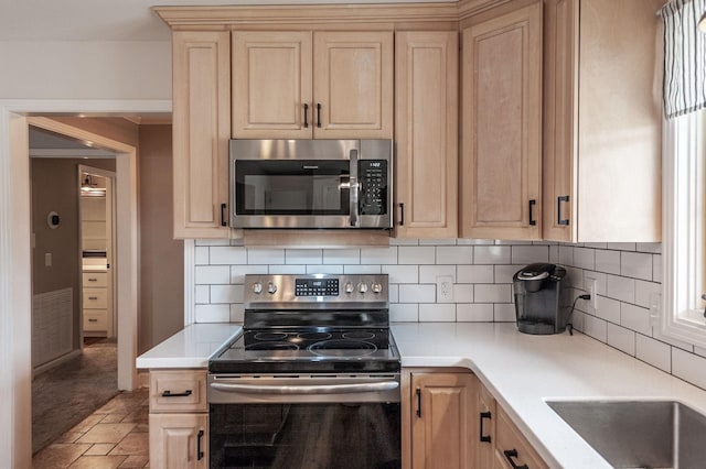 kitchen with stone finish floor, light brown cabinets, appliances with stainless steel finishes, and light countertops